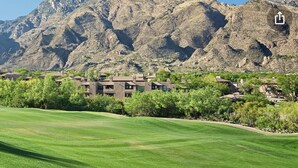 Un campo de golf con vistas a montañas y edificios residenciales al fondo.