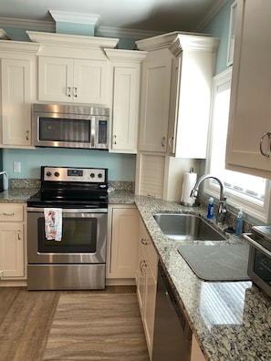 A modern kitchen with white cabinets, stainless steel appliances, granite countertops, and a built-in sink. - Amazing sunsets and ocean breezes await you at this beautiful beach view home. (Port St Joe)