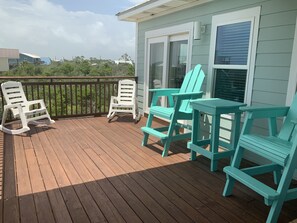 A wooden deck with two rocking chairs and a table, overlooking a residential area. - Amazing sunsets and ocean breezes await you at this beautiful beach view home. (Port St Joe)