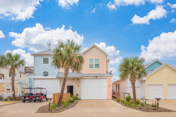 A two-story house with a garage, a satellite dish, and a golf cart parked in front.