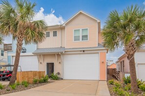 A two-story house with a garage, a driveway, and a wooden fence. - Studio w/ Private hot tub after 10/11, no stairs (Port Aransas)