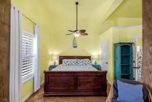 A bedroom with a wooden bed, a ceiling fan, a window with blinds, and a teal cabinet. - Studio w/ Private hot tub after 10/11, no stairs (Port Aransas)