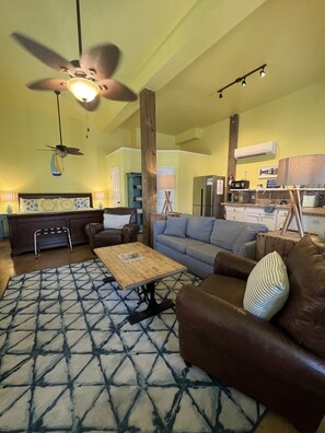 A living room with a ceiling fan, a coffee table, a sofa, and a patterned rug. - Studio w/ Private hot tub after 10/11, no stairs (Port Aransas)
