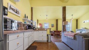 Une cuisine compacte avec des meubles blancs, une machine à café et un coin repas comprenant une table et des chaises.