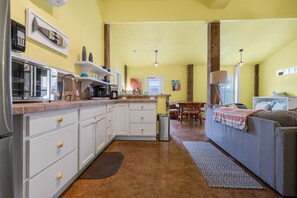 A compact kitchen with white cabinets, a coffee maker, and a dining area with a table and chairs. - Studio w/ Private hot tub after 10/11, no stairs (Port Aransas)