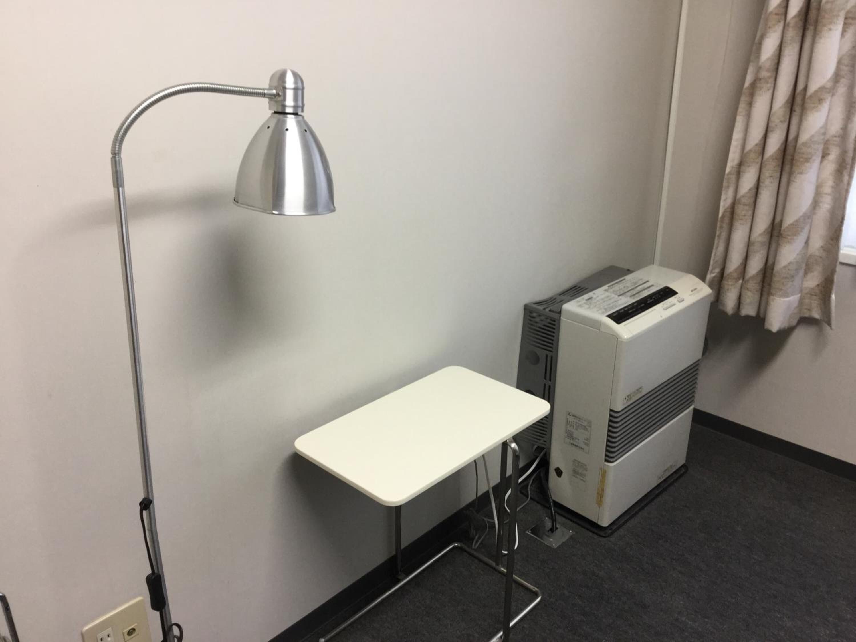 A small office space with a desk, a lamp, and an air conditioning unit.