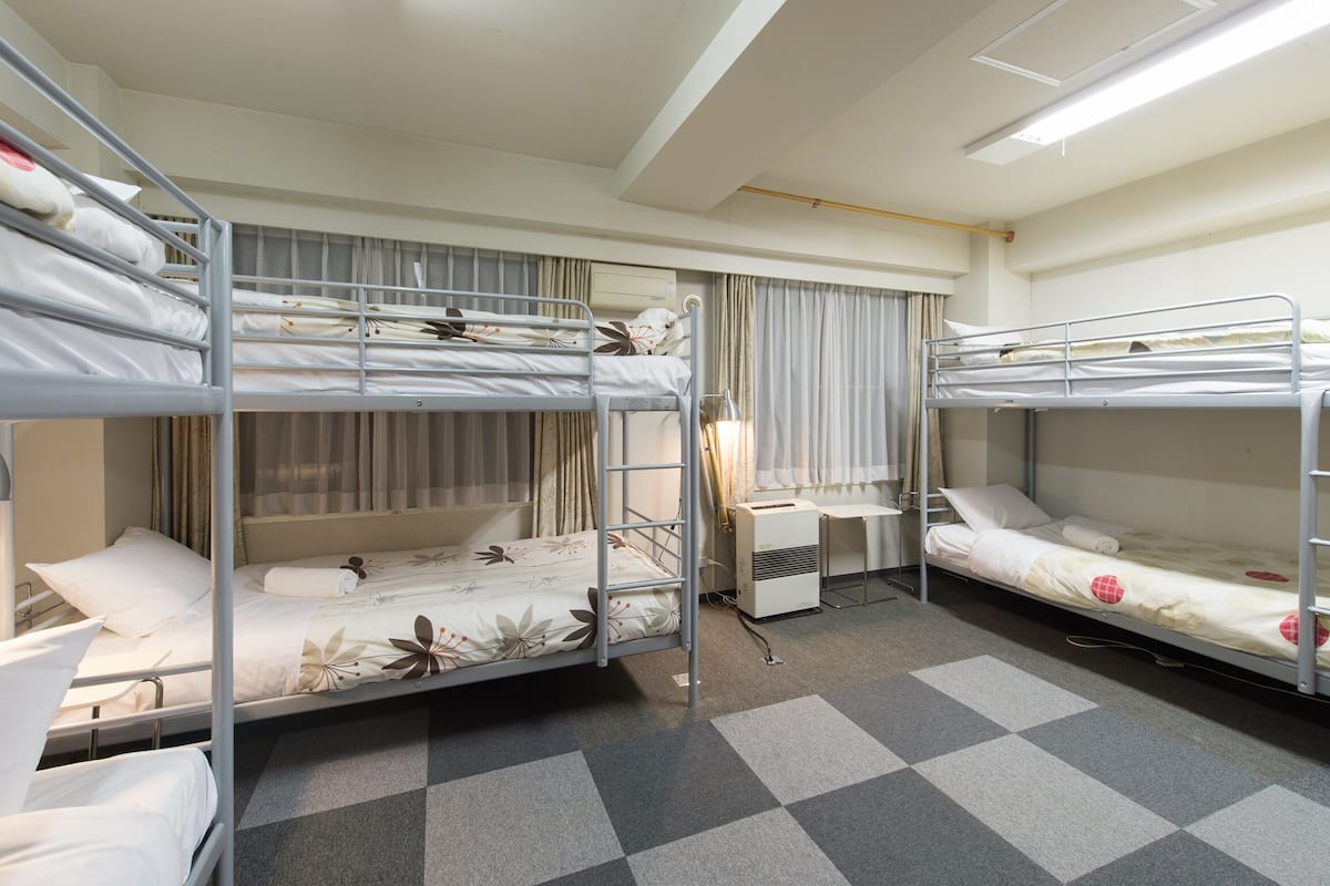 A hotel room with three bunk beds, a desk, and a chair.