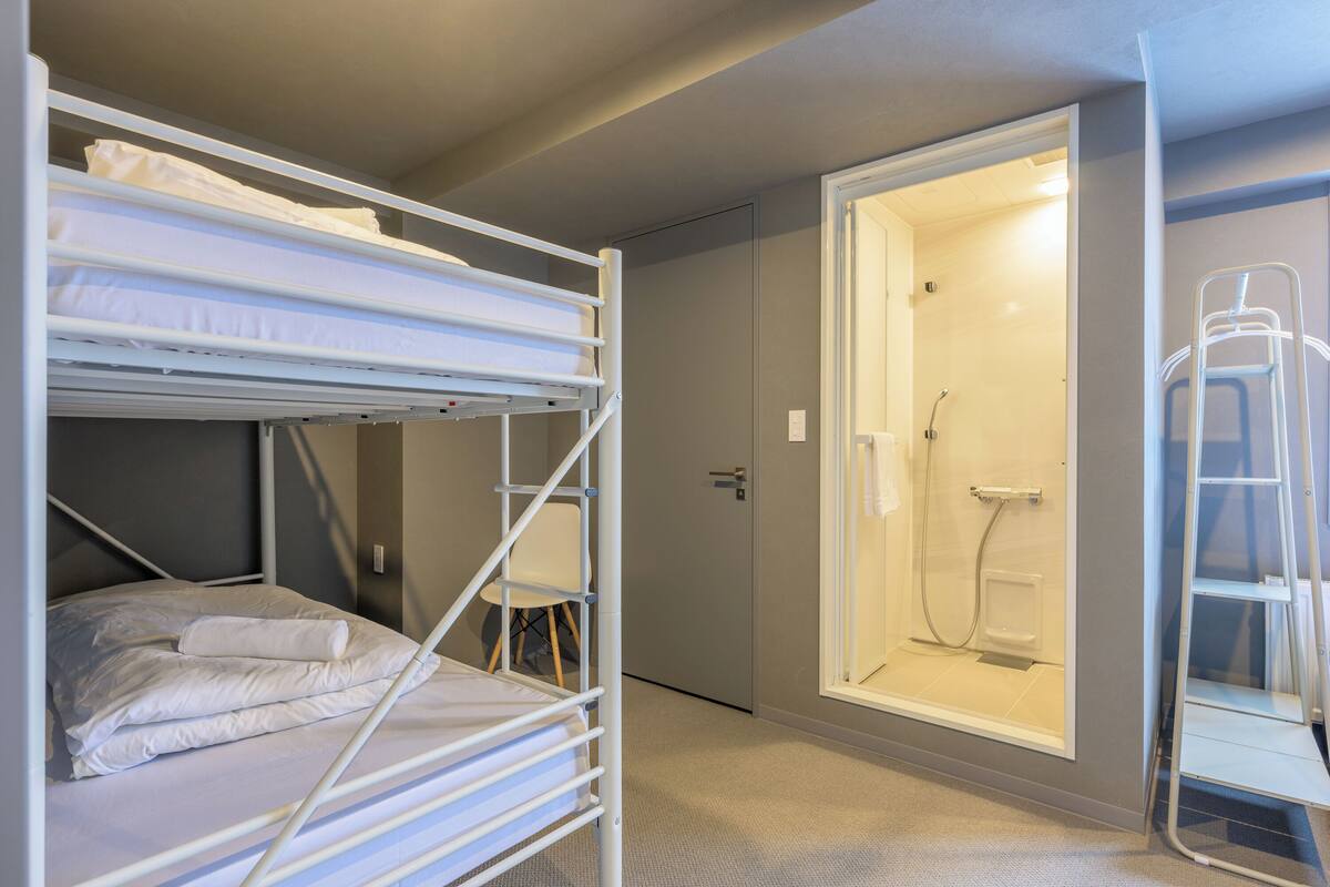 A bunk bed with a shower area and a ladder.