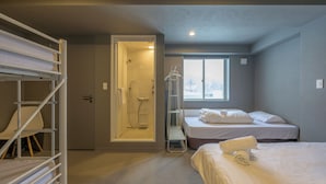 Una habitación de hotel con literas, ducha a pie, ventana y cama bien hecha.