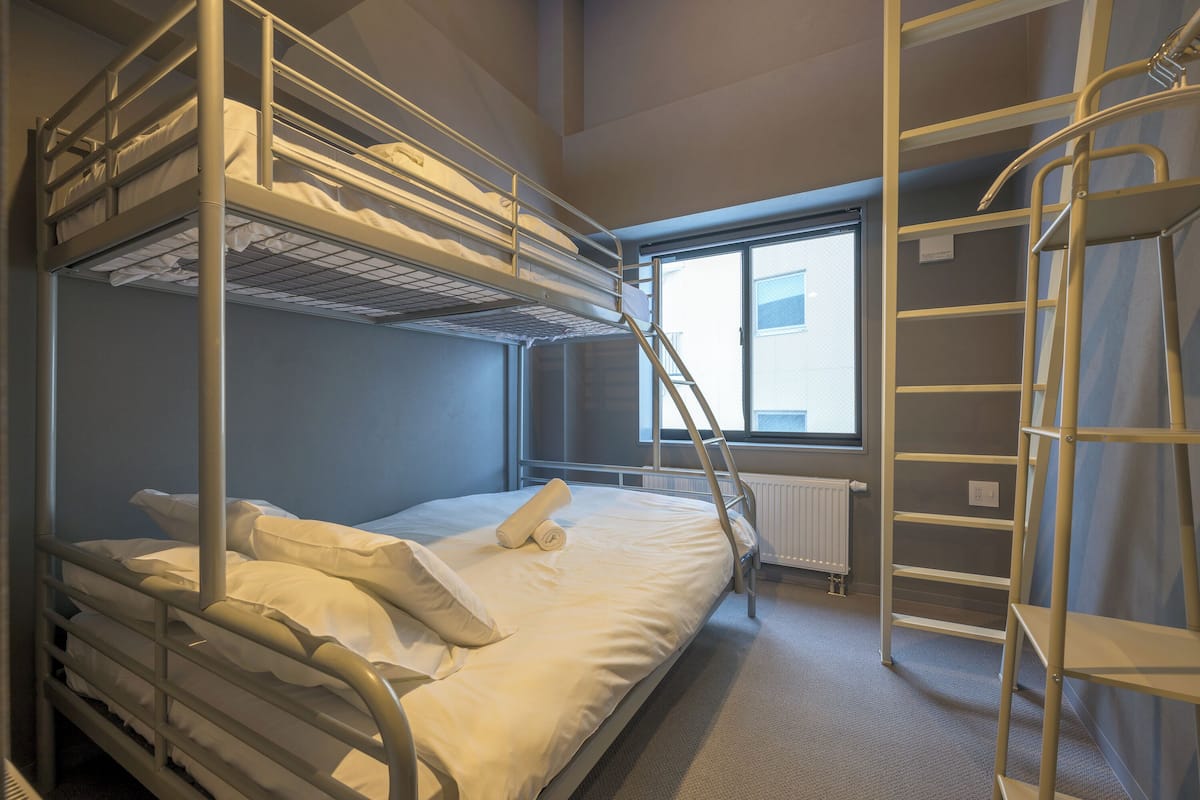 A bunk bed room with a window, a radiator, and a metal ladder.