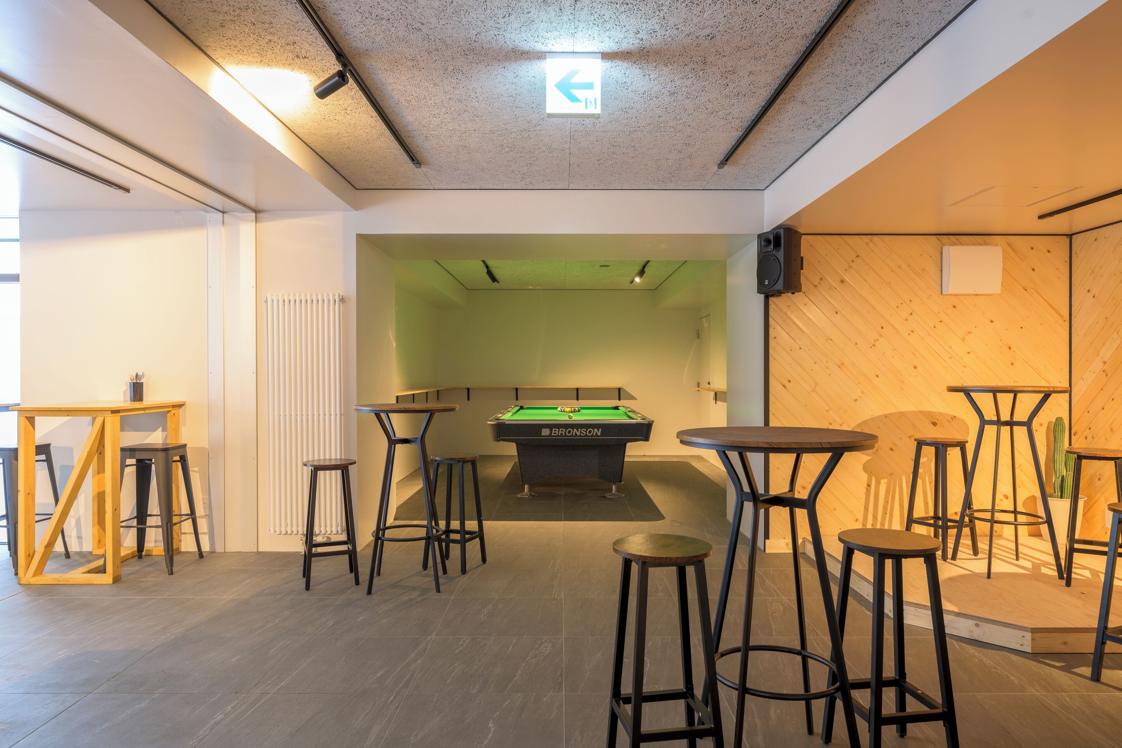 A billiards room with a pool table, stools, and a wooden wall.