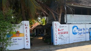 Welkomstbord voor Star Rest Beach Hotel in Arugambay, met een illustratie van een strand en een advertentie voor surfles.