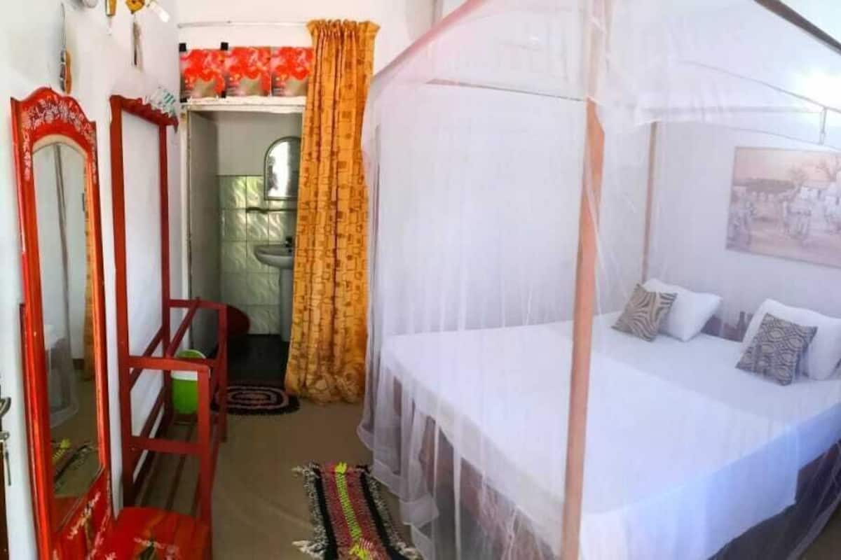 Ein Schlafzimmer mit einem Bett, einem Nachttisch, einem Spiegel und einem Fenster.