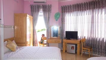 Un dormitorio con una cama, un escritorio con televisor y un refrigerador pequeño.