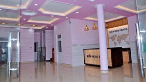 A hotel lobby with a modern ceiling design, a reception desk, and a glass partition. - Bien Ngoc Ly Son Hotel (Ly Son)