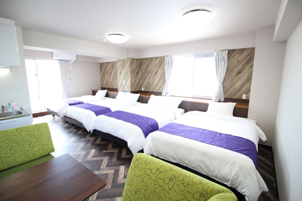 A hotel room with two beds, a wooden floor, a small table, and a chair.