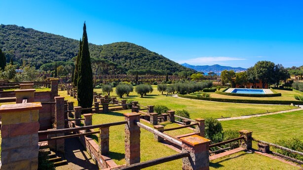 An ancient ruin with stone walls and columns, surrounded by well-maintained gardens and a clear blue sky. - Appartamento Via Dei Lecci - APPARTAMENTO I LECCI (Rio nell'Elba)