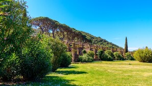 A historic building complex with stone structures and lush greenery. - Appartamento Via Dei Lecci - APPARTAMENTO I LECCI (Rio nell'Elba)