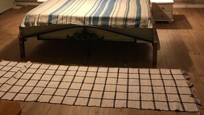 Un dormitorio con cama, dos mesitas de noche, una ventana y techo inclinado.