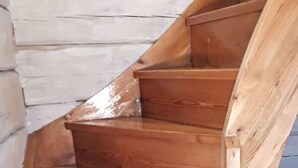 Una escalera de madera con barandilla, que conduce a un piso superior.