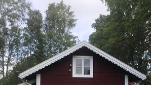 Una casa de madera roja con un ventanal blanco y un pequeño porche.