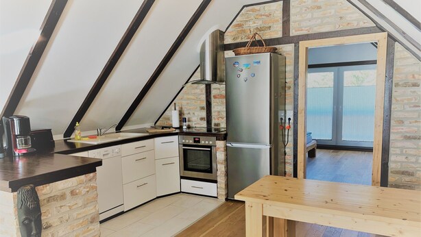 Una cocina con pared de ladrillo, una mesa de madera y un refrigerador.