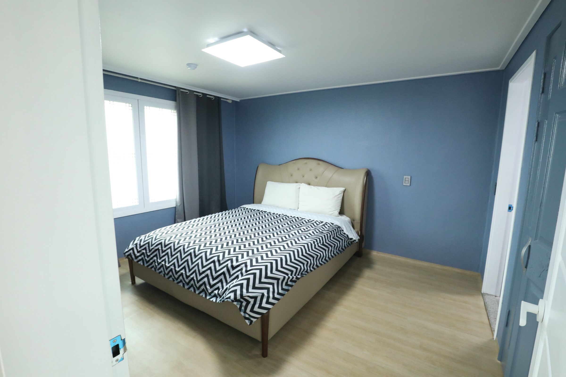 Un dormitorio con cama, ventana y puerta.