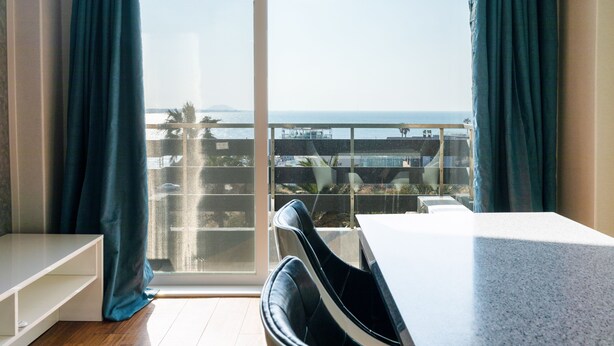 A room with a large window, a white table, and a black chair. - Jeju Tovice Condo Ocean (Jeju City)