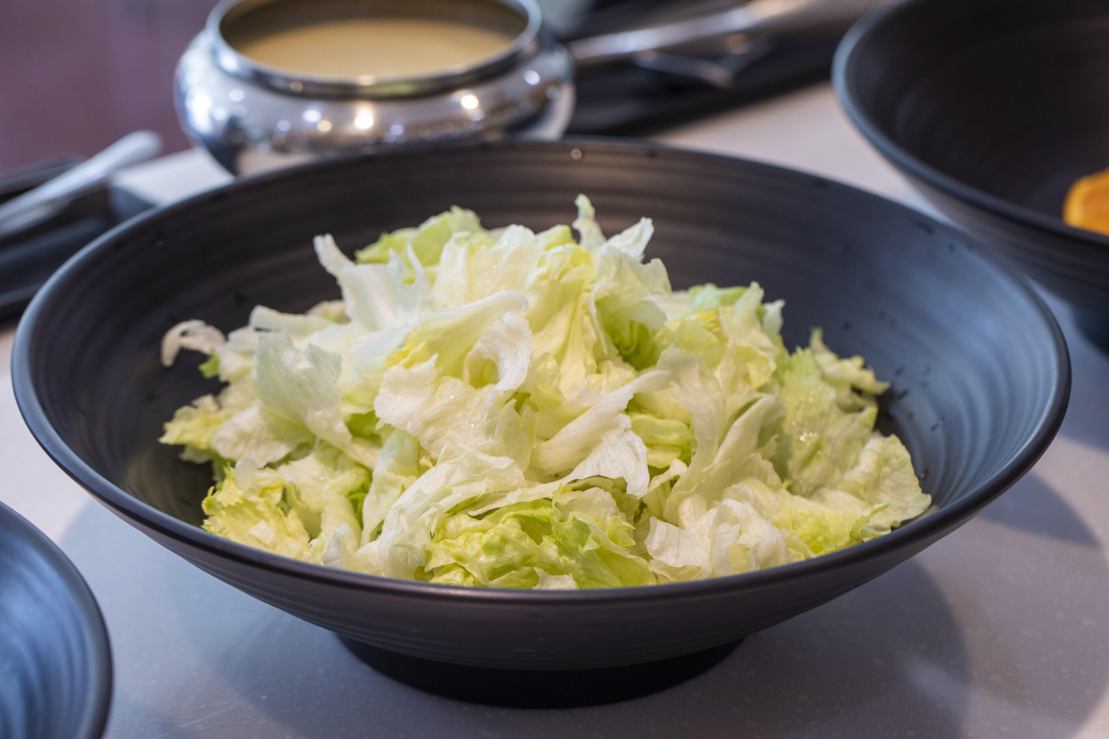 A bowl of shredded lettuce on a table.