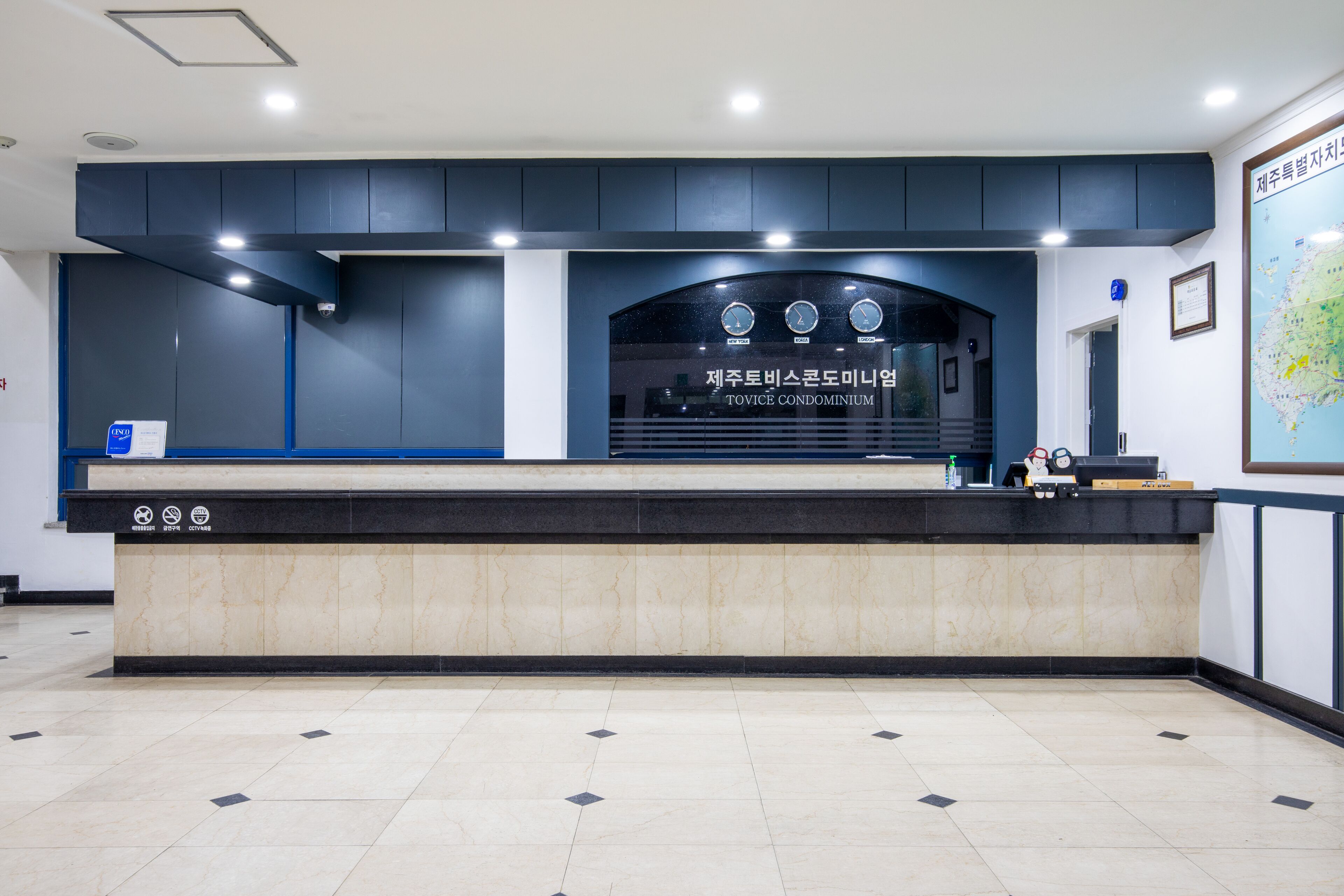 A reception desk with a sign reading "TOVICE CONDOMINIUM" and a map on the wall.