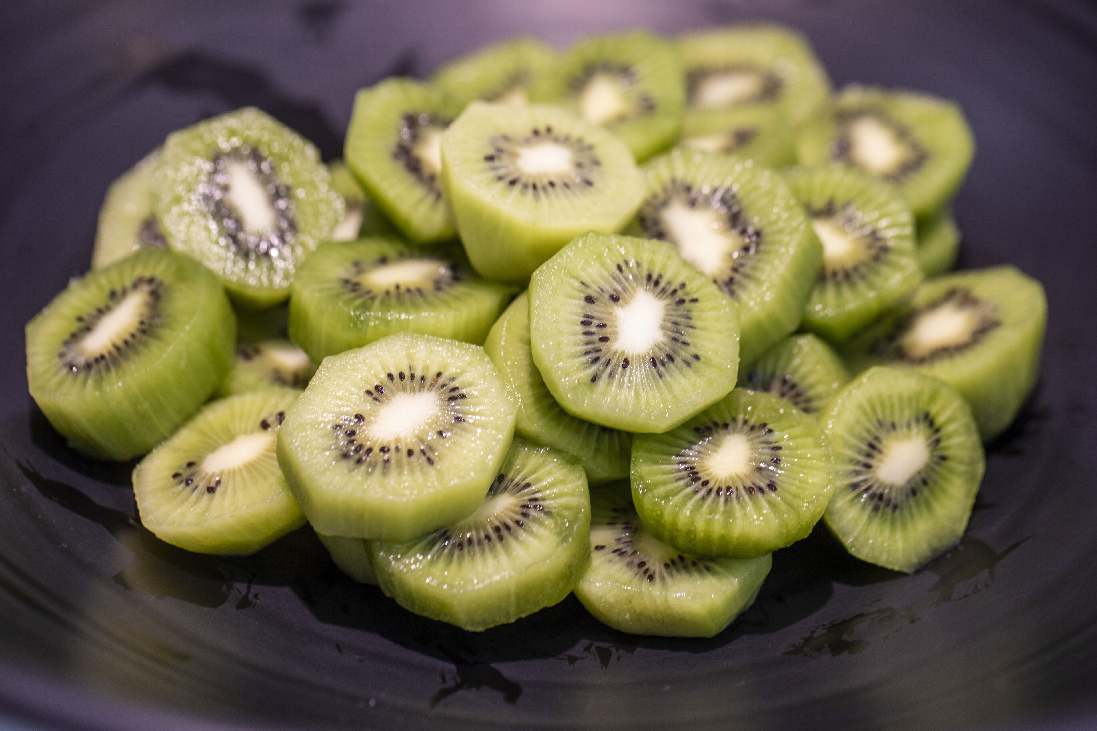 Primer plano de rodajas de kiwi sobre una superficie oscura.
