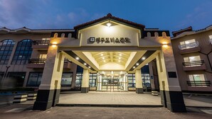 A hotel entrance with a covered walkway, large windows, and a sign above the entrance. - Jeju Tovice Condo Ocean (Jeju City)