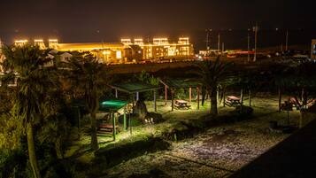 A nighttime view of a well-lit industrial area with buildings, a parking lot, and a small park with picnic tables and benches.