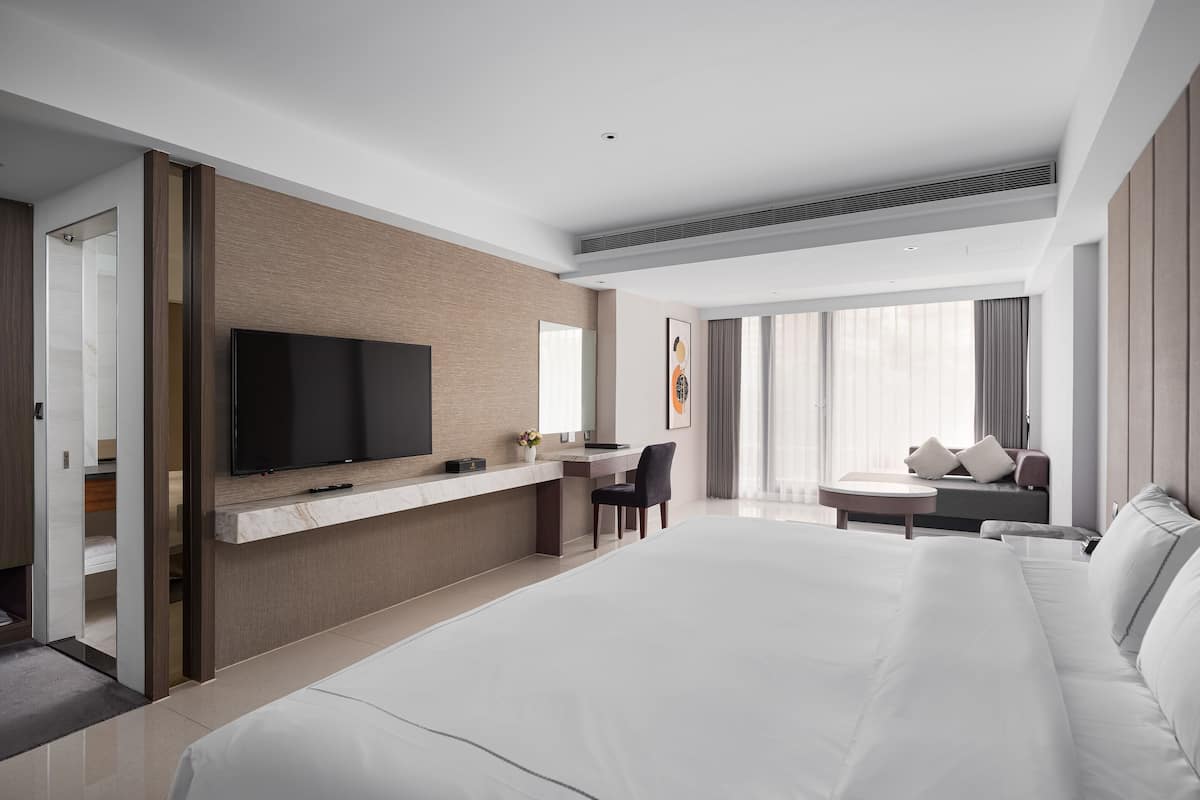 A modern hotel room with a large bed, a desk, and a TV.