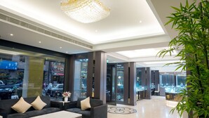 A modern lobby with a chandelier, seating area, and glass display cases. - Gamalan Spring Hotel (Jiaoxi)