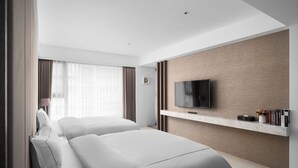 A modern hotel room with two beds, a TV mounted on a wooden panel, a small shelf with books and a vase, and a window with curtains. - Gamalan Spring Hotel (Jiaoxi)