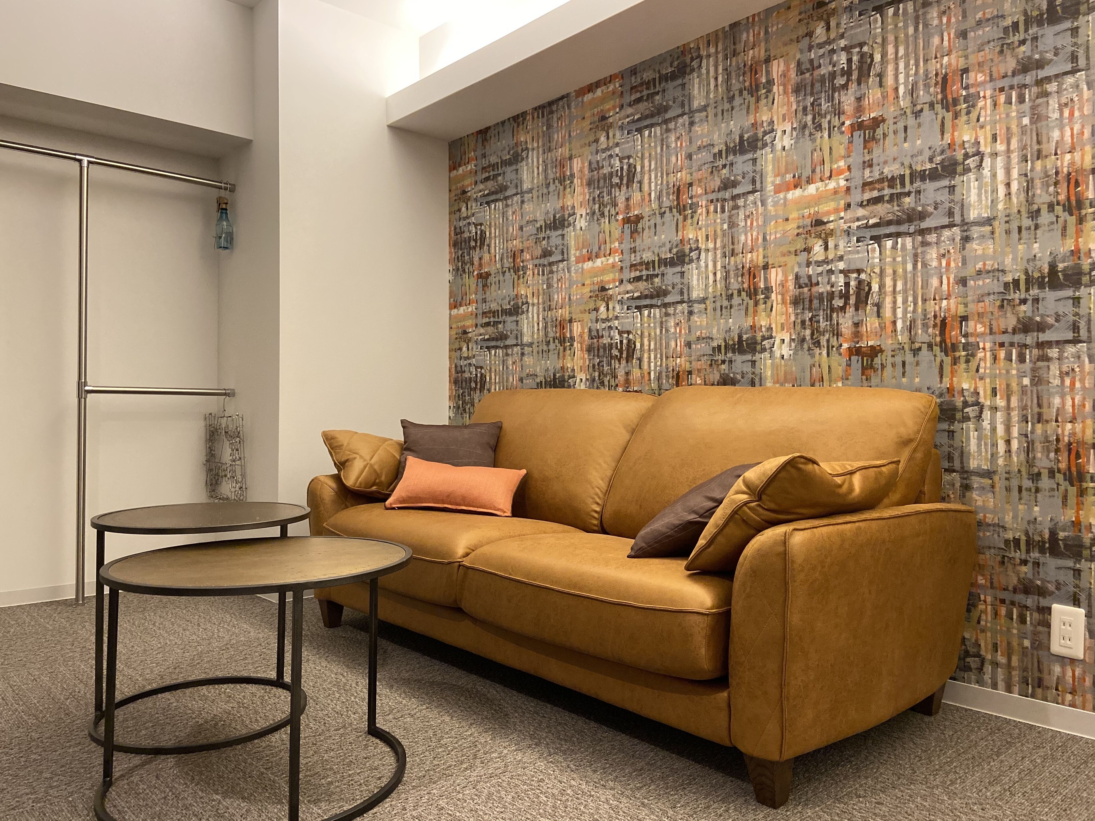A modern living room with a sofa, a small round table, and a patterned wall.