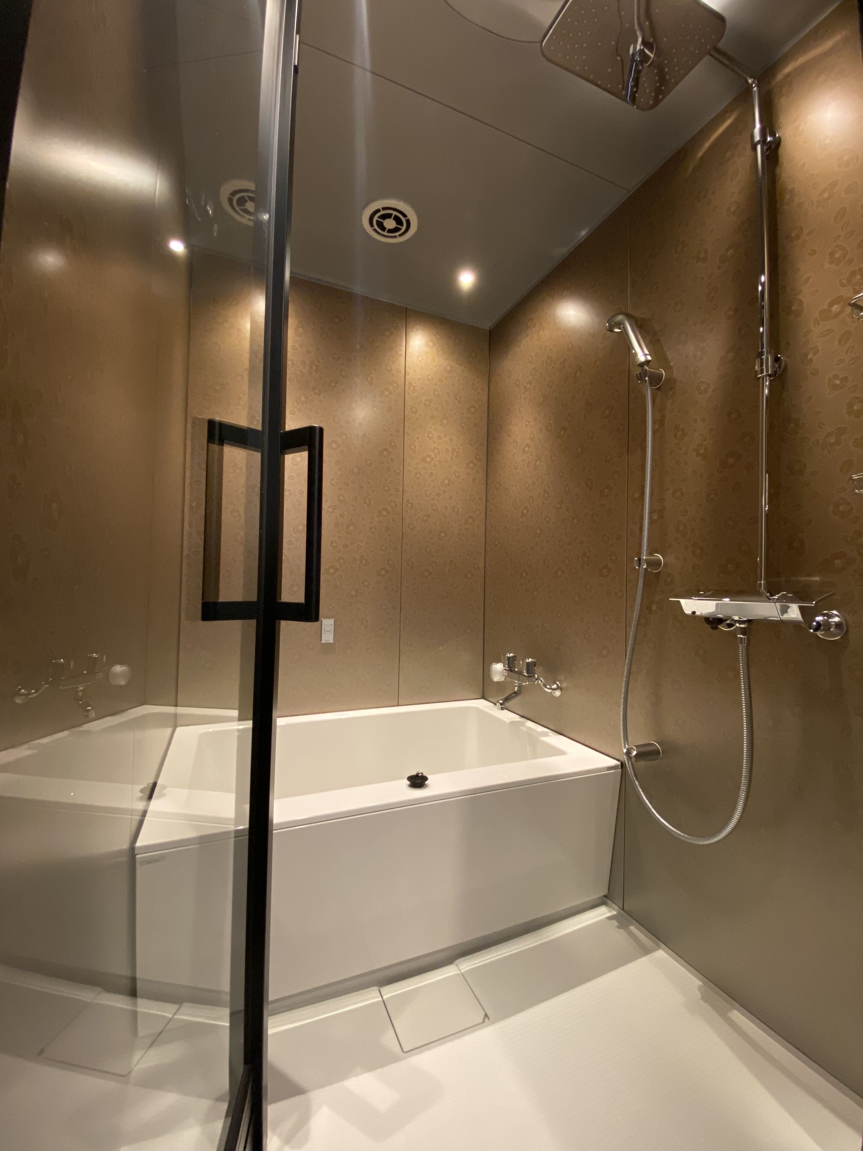 A modern bathroom with a glass-enclosed shower, a standalone bathtub, and a wall-mounted toilet.