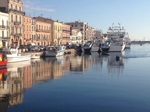 A marina with various boats docked along a waterfront, surrounded by historic buildings.