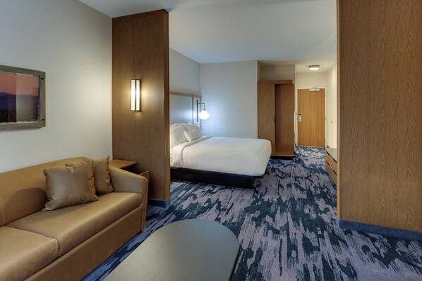 A hotel room with a bed, a sofa, a desk, and a carpeted floor. - Fairfield Inn & Suites by Marriott Asheville Weaverville (Weaverville)