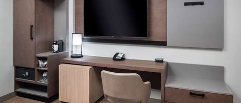 A modern office space with a desk, chair, and built-in TV.