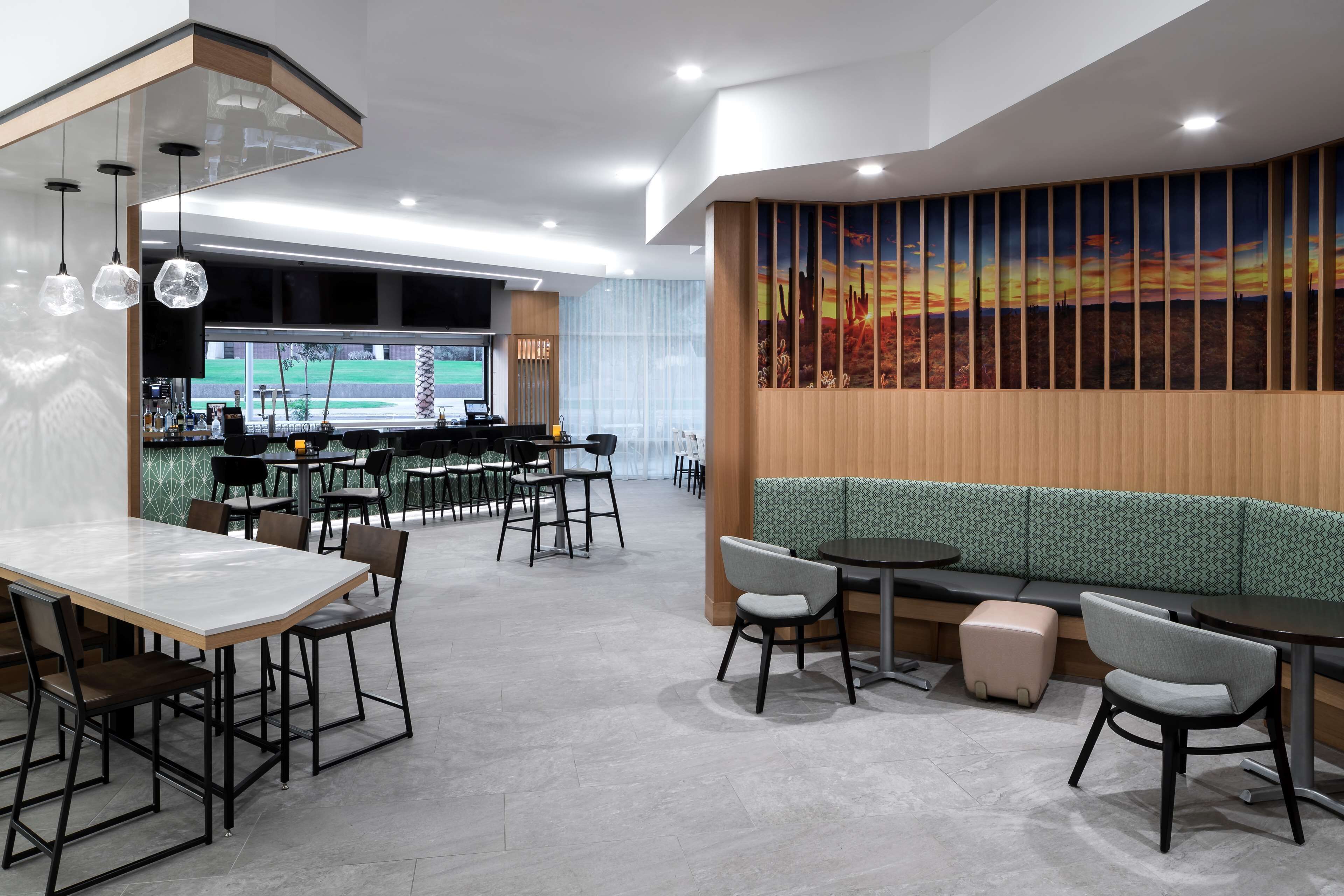 A modern restaurant with a bar area, seating arrangements, and a large wall mural.