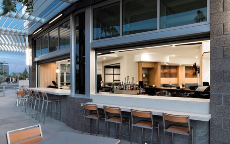 An outdoor bar area with a modern design, featuring a counter with bar stools and a view of the interior.