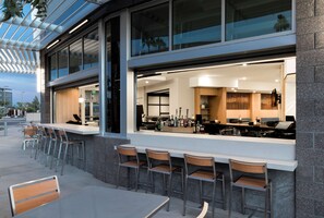An outdoor bar area with a modern design, featuring a counter with bar stools and a view of the interior. - Hyatt Place Tempe / Phoenix / University (Tempe)