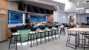 Une cuisine moderne dotée d’un bar, de grandes fenêtres et d’un espace repas avec des tables et des chaises.