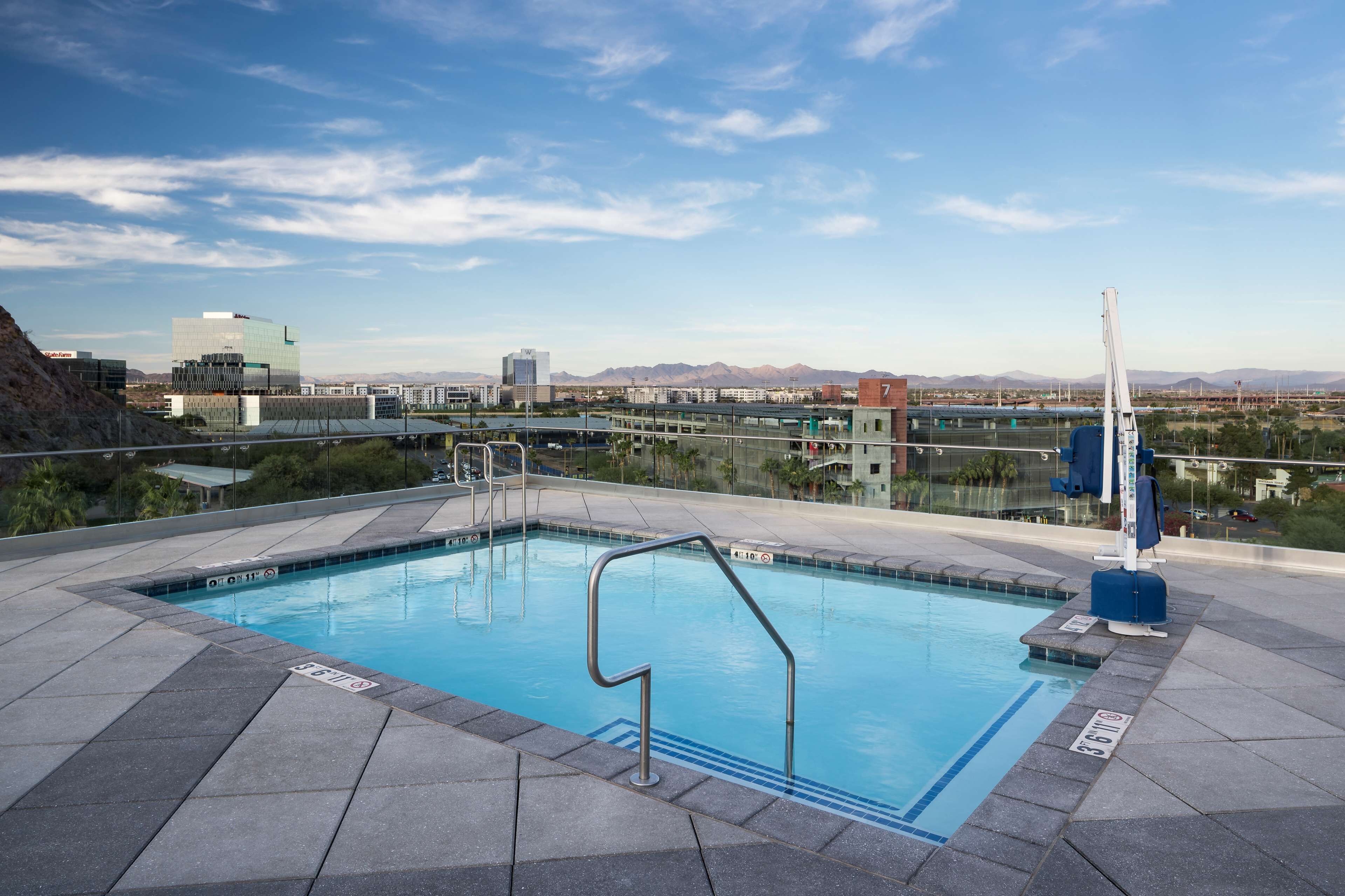 A rooftop pool with a view of distant mountains and buildings.