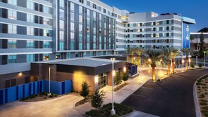 Un hôtel moderne à plusieurs étages, doté d’un espace extérieur couvert et d’un parking.