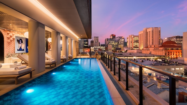 A rooftop infinity pool with lounge chairs and a cityscape view at dusk. - Hotel Indigo Adelaide Markets by IHG (Adelaide)