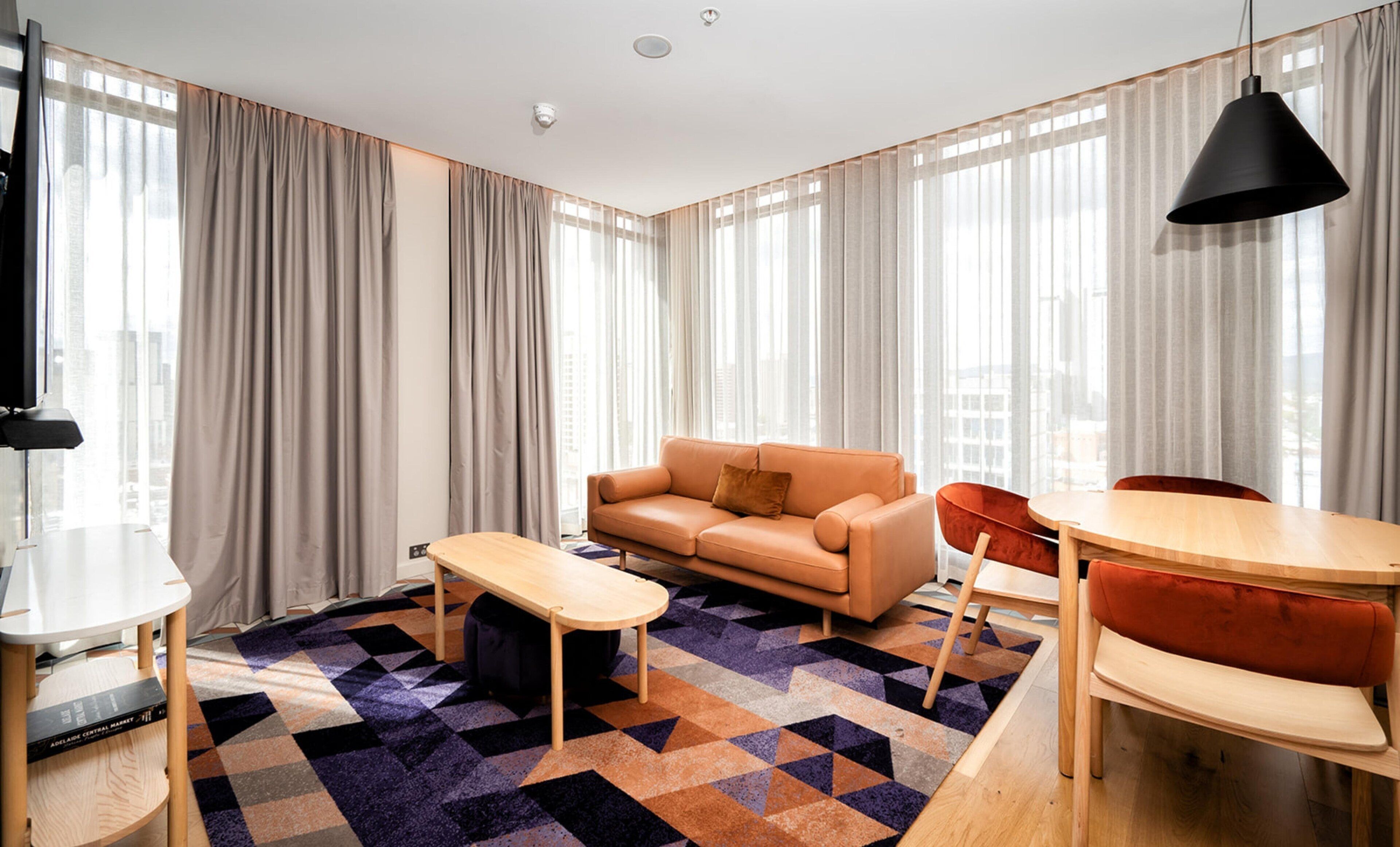 Un salon moderne comprenant un canapé, une table basse et un coin repas avec des chaises.