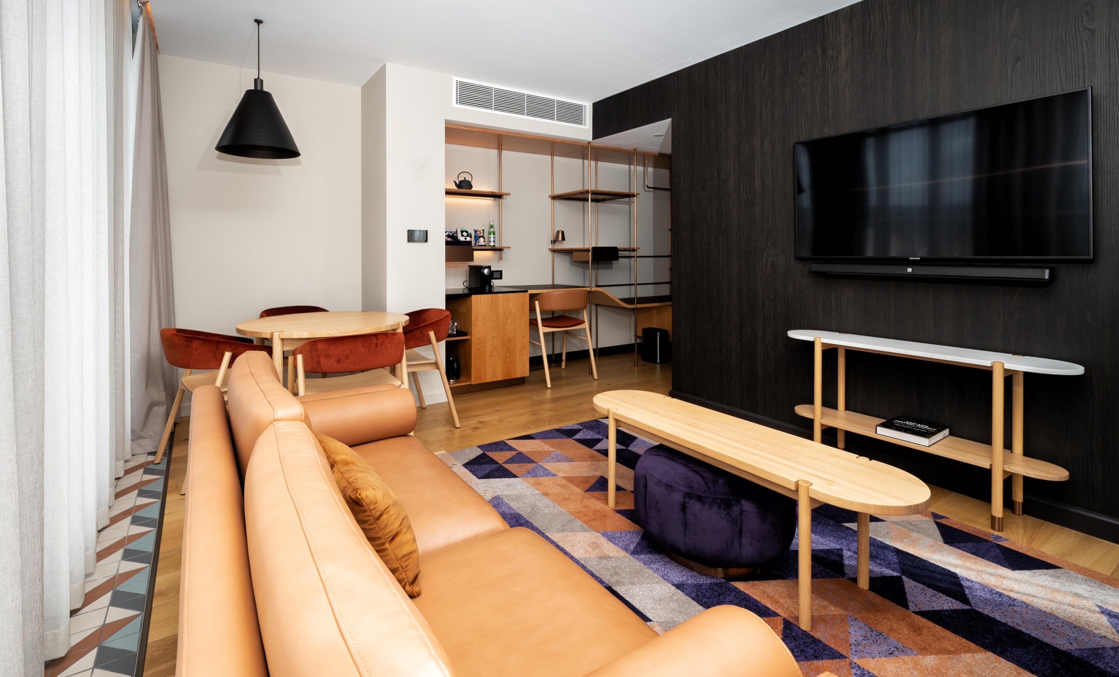 A modern living room with a sofa, a coffee table, and a TV mounted on the wall.